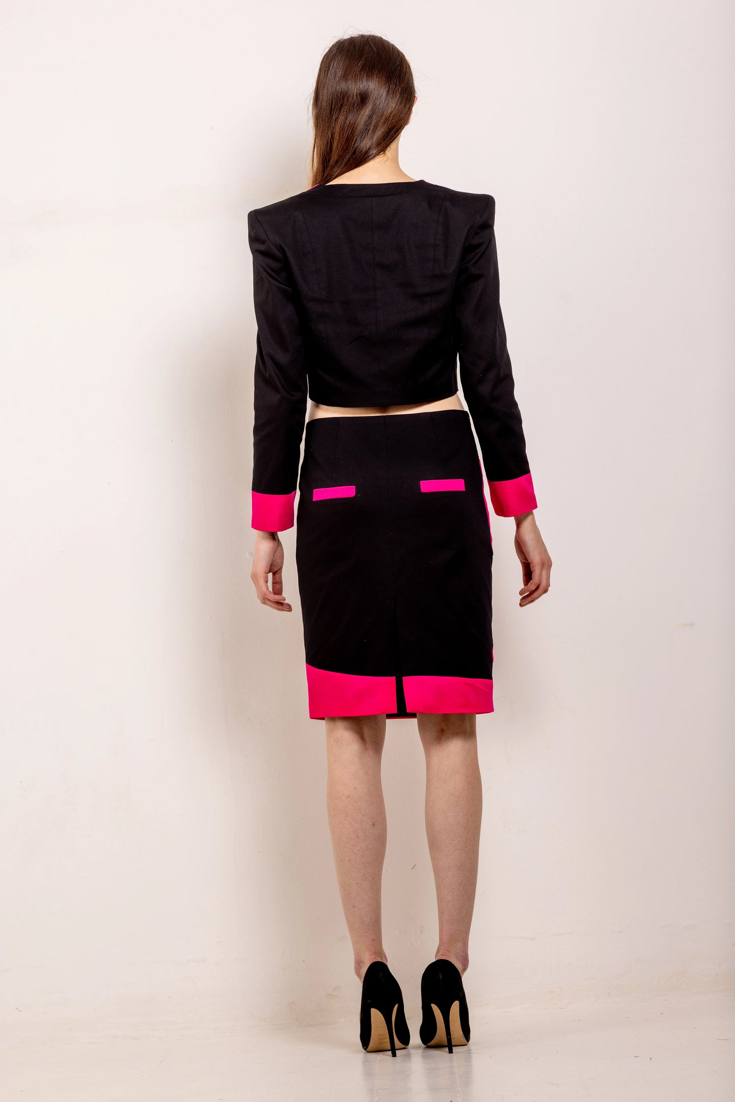 Ensemble tailleur femme noir avec veste courte à finitions fuchsia et jupe crayon assortie, coupe structurée, confection italienne en série limitée.
